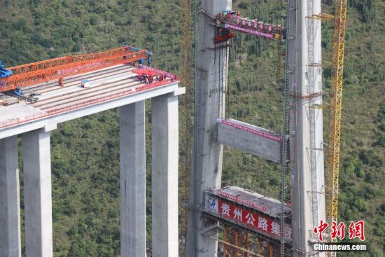 11月22日，峰林特大橋4號主塔中橫梁正在吊裝。當日，隨著1470噸裝配化預制中橫梁提升到位，貴州省黔西南布依族苗族自治州興義環(huán)城高速公路峰林特大橋4號主塔中橫梁成功吊裝，由此刷新了山區(qū)峽谷橋梁預制吊裝混凝土構件重量世界記錄。峰林特大橋是屬全線控制性工程。大橋跨越馬嶺河峽谷，全長1163米，主跨采用550米懸索橋，橋面離谷底364.2米，是中國山區(qū)第一座大跨徑鋼混疊合梁懸索橋。中新社記者 瞿宏倫 攝